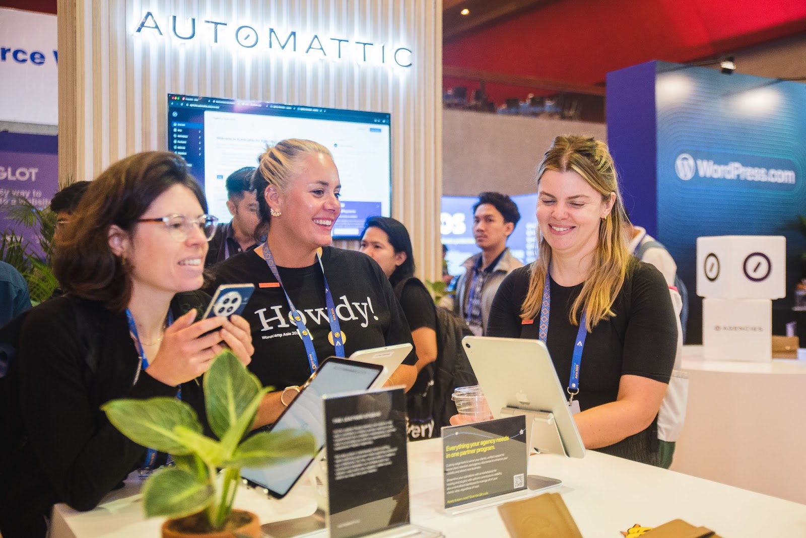 several people gathered around the Automattic for Agencies booth at WordCamp Asia